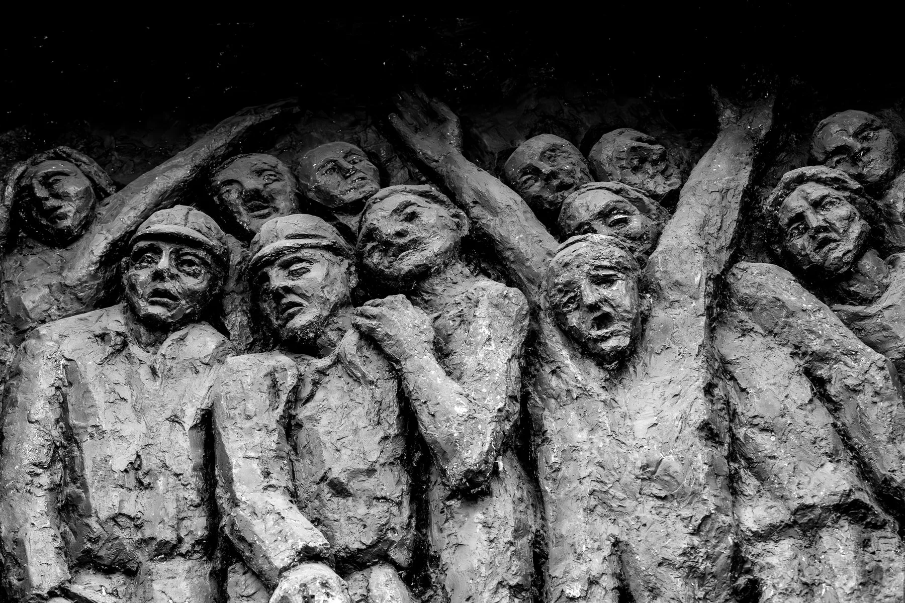 Fragment pomnika Tragedii Górnośląskiej w Bytomiu: rzeźbiona grupa postaci z uniesionymi ramionami.